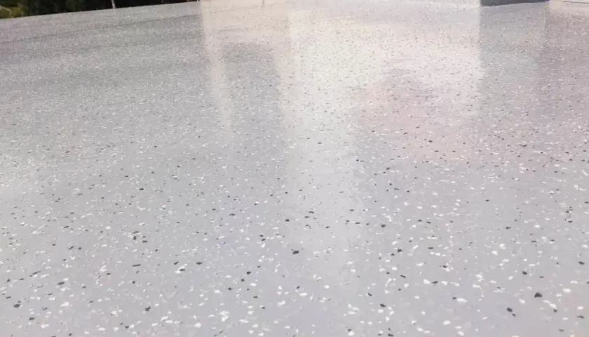 Nowoczesny kamienny dywan koszt 1m2. Jasnoszara posadzka z drobnymi, kolorowymi płatkami, idealna na taras lub balkon.