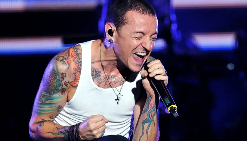 Chester Bennington, wokalista zespołu, śpiewa z pasją na koncercie. Jego ramiona pokryte są kolorowymi tatuażami.