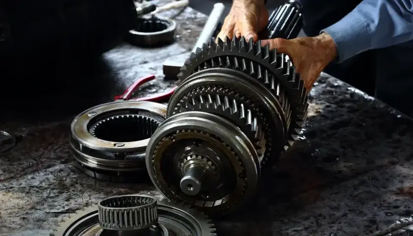 Mechanik składa elementy skrzyni biegów. Zastanawiasz się, ile kosztuje wymiana skrzyni biegów?