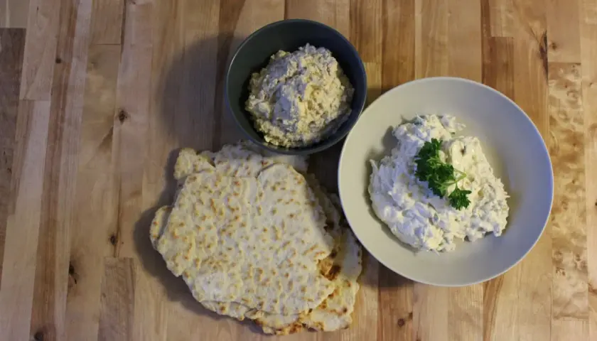 Två skålar med krämig tarator djej, en med persilja, bredvid tunna, krispiga bröd.