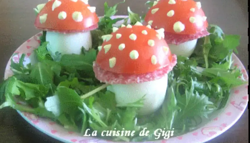 Trois adorables champignon œuf, décorés de tomate et de points blancs, reposent sur un lit de verdure.