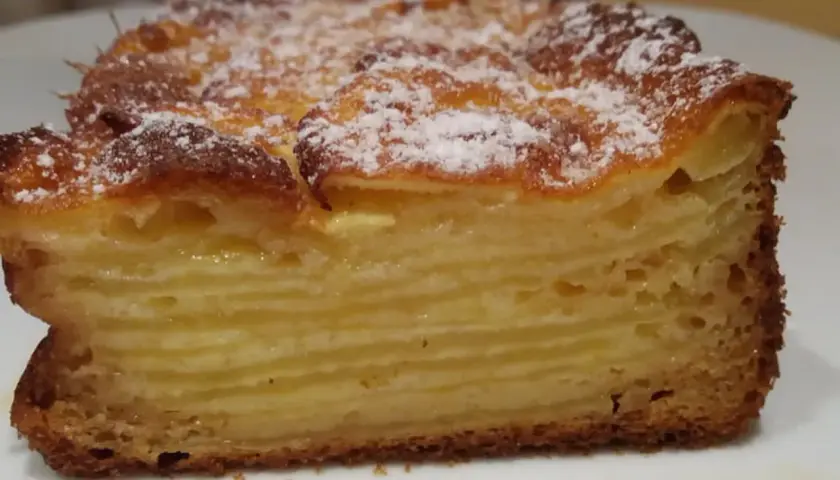 Une tranche de gâteau aux pommes, avec des couches fines et dorées, saupoudrée de sucre glace. Un délice invisible aux pommes.