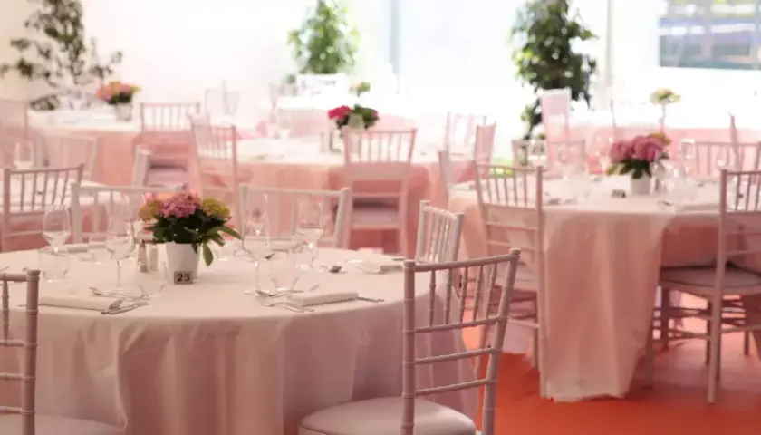 Tables dressées pour un mariage sans traiteur, avec des chaises blanches et des centres de table floraux.