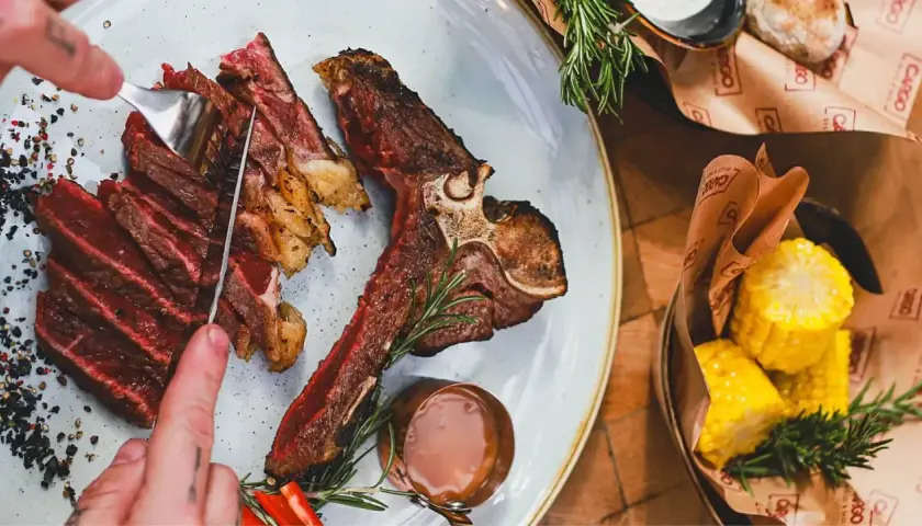 Soczysty stek T-bone, pokrojony w plastry, z pieprzem i rozmarynem. Idealny wybór, jeśli zastanawiasz się, jakie wino do steka.
