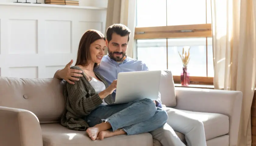 Couple planifiant l'amélioration de leur habitat, consultant un prêt sur leur ordinateur.