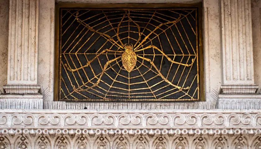 Ragno dorato su ragnatela nera, dettaglio architettonico del quartiere Coppedè interni.