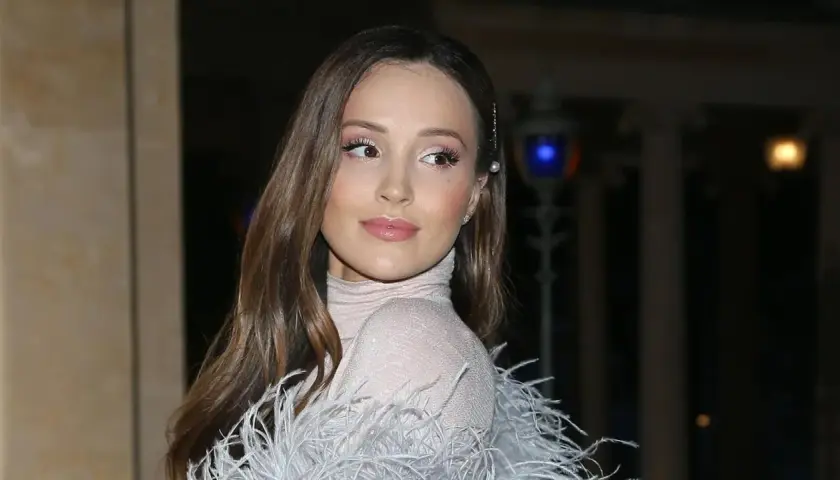 Elegancka żona Szczęsnego w błyszczącej sukni z piórami, z delikatnym makijażem i perłową spinką we włosach.