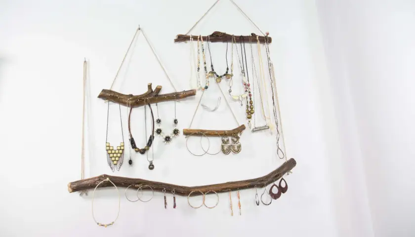 Colgante rústico con ramas de madera, ideal para exhibir collares y pendientes. Un ejemplo de manualidades de madera para adultos, con un toque bohemio.