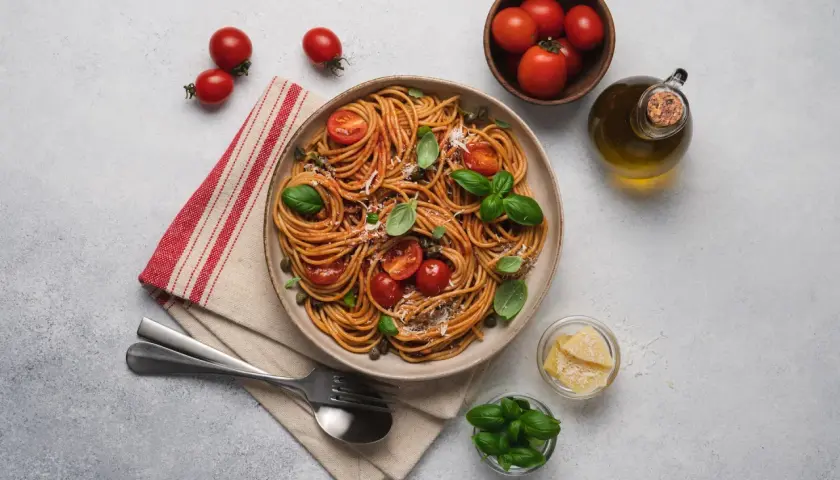 Pyszne spaghetti z pomidorami i bazylią, idealne na dietę SIBO. Oliwa, parmezan i świeże zioła dopełniają danie.