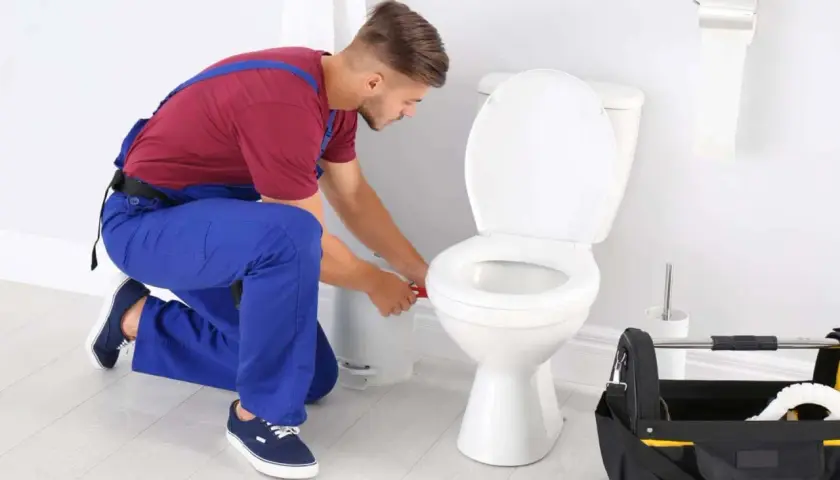 Idraulico al lavoro per sostituire guarnizione scarico WC. Attrezzi a portata di mano.