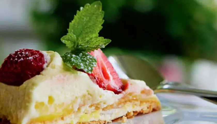 En bit pavlova med lemoncurd, toppad med färska jordgubbar och mynta. En härlig dessert som smälter i munnen.