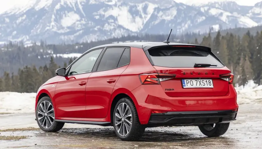 Czerwona Skoda Fabia Monte Carlo z czarnym dachem na tle ośnieżonych gór.
