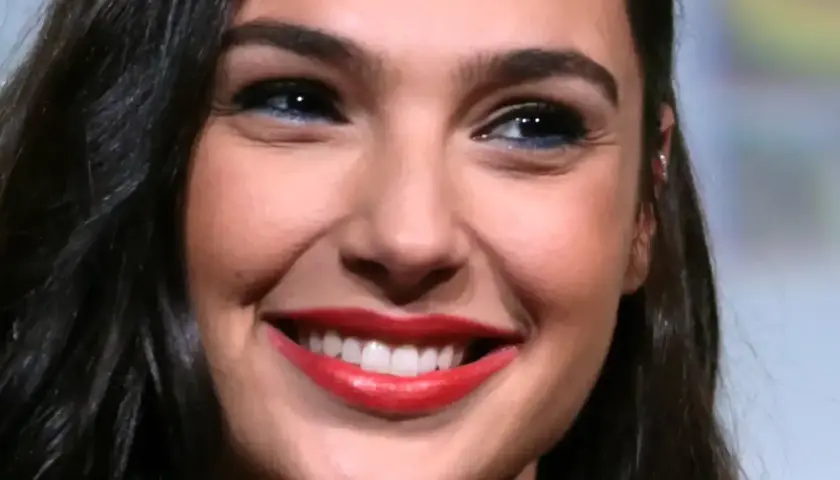 Zbliżenie na twarz Gal Gadot z szerokim uśmiechem i czerwonymi ustami.