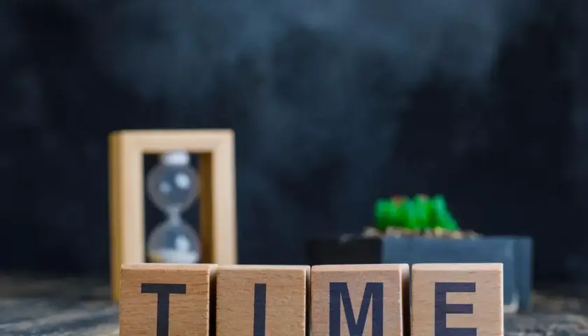Blocchi di legno con la parola TIME, clessidra e pianta. È mezzanotte, il tempo scorre.