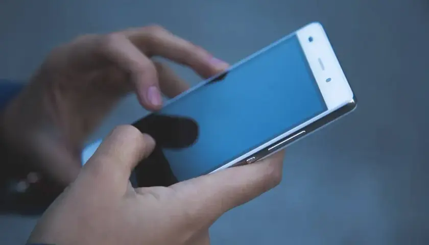 Dłonie trzymające smartfon. Zastanawiasz się, jak odzyskać telefon zatrzymany przez policję?