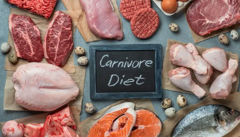 Różnorodne mięsa, ryby i jaja na stole. Tabliczka z napisem "Carnivore Diet" sugeruje, że to inspiracja dla osób szukających efektów diety karniwora.