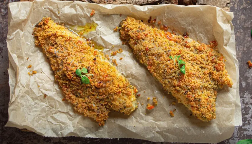 Filetti di orata in padella gratinati, dorati e croccanti, guarniti con erbe fresche.