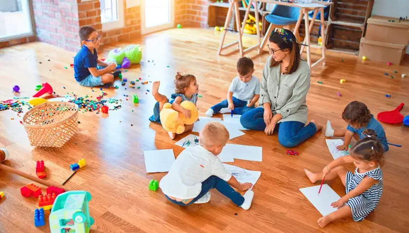 Niños de guardería de 2 años dibujan y juegan en el suelo.