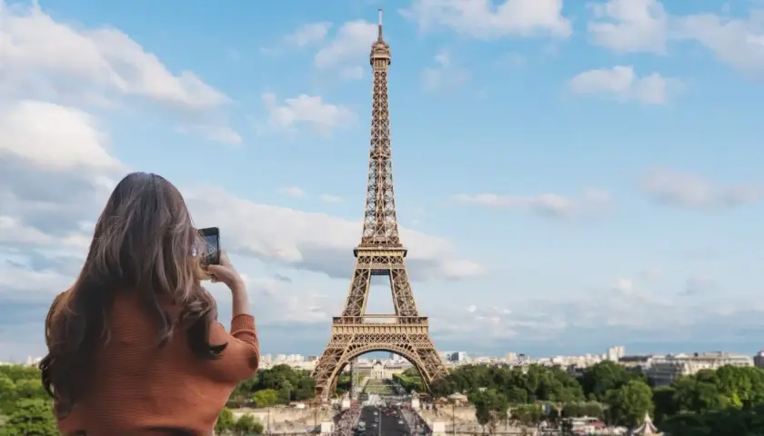 Kobieta robi zdjęcie telefonem ikonicznej wieży Eiffel.