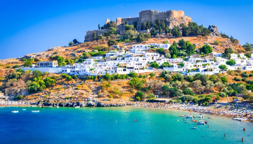 Lindos auf Rhodos: weiße Häuser, Burgruine und ein belebter Strand. Tolle Rhodos Urlaub Tipps für deine Reise!