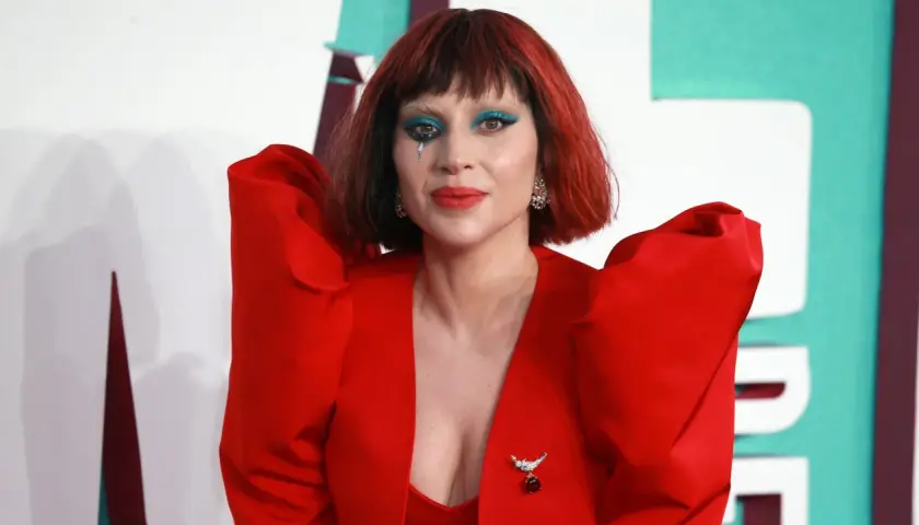 Lady Gaga w czerwonym, teatralnym stroju z niebieskim makijażem oczu i łzą na policzku. Fani marzą o koncercie Lady Gaga w Polsce.