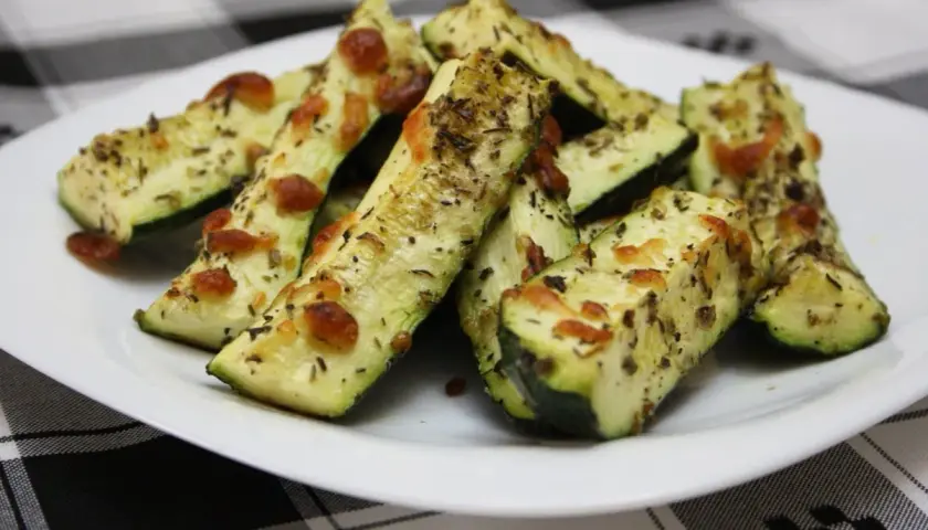 Delicioso calabacín al horno, cortado en bastones y cubierto con queso derretido y hierbas aromáticas.