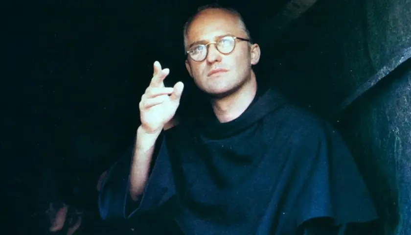 Aktor w filmie o Maksymilianie Kolbe, w okularach i habicie, gestykuluje.