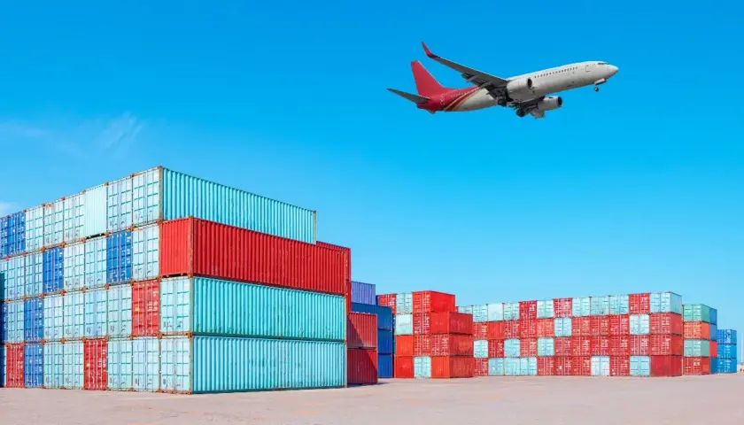 Frachtflugzeug über Containerstapeln. Die IATA Bedeutung für globalen Handel wird hier visuell dargestellt.