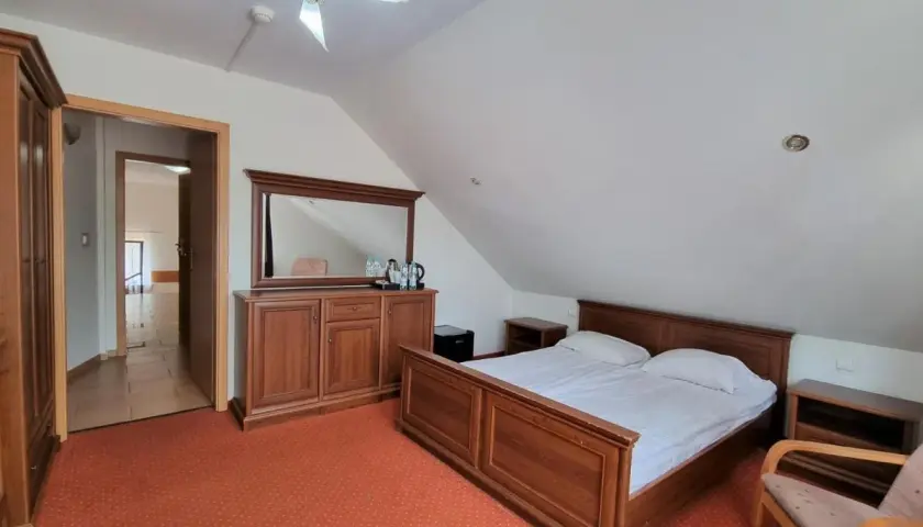 Przytulny pokój z łóżkiem, szafą i komodą z lustrem. Idealne miejsce na wypoczynek w Paradiso Park Pobierowo.
