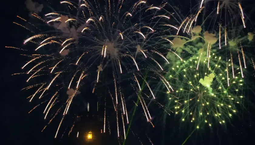 Pokaz sztucznych ogni nad ciemnym niebem, z widocznym fragmentem wieży.