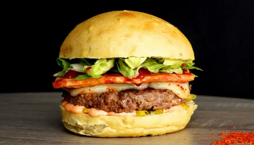 Un généreux burger savoyard avec un steak juteux, fromage fondant, légumes frais et une touche de piment sur un pain brioché.