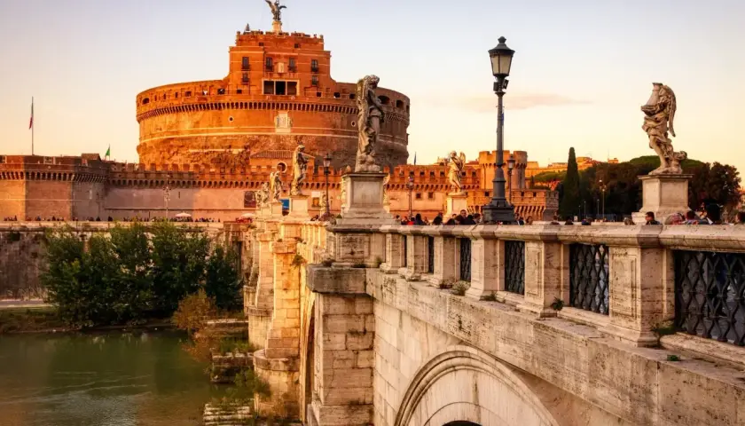 Le pont Saint-Ange à Rome, orné de statues d'anges, mène au château Saint-Ange au coucher du soleil.
