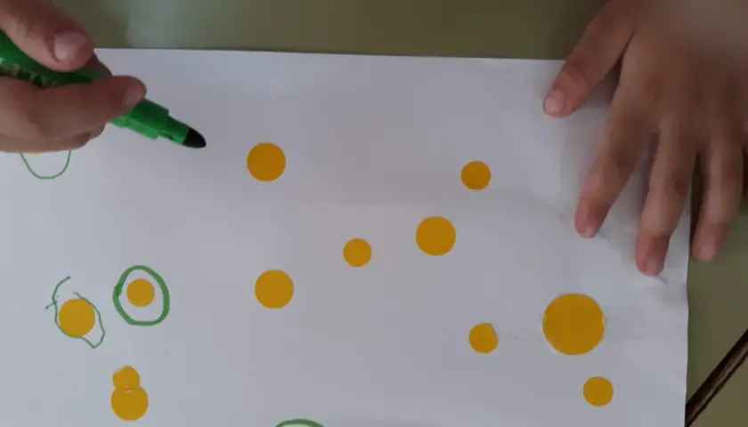 Manos de niño creando círculos y puntos, inspirándose en las kandinsky obras para niños.