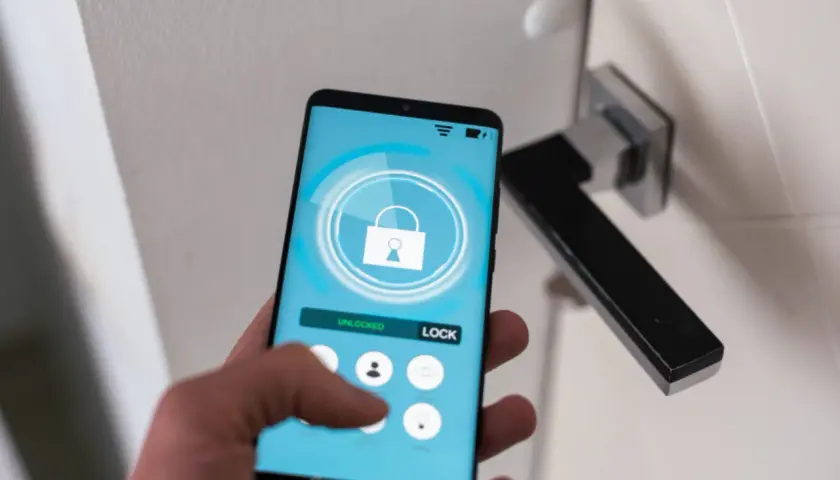 Smartfon z aplikacją do zarządzania domem. Widoczny przycisk "LOCK" i ikona kłódki. Ułatwia to check in.