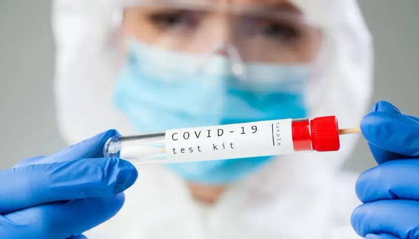 Osoba w kombinezonie ochronnym trzyma probówkę z wymazem. Zastanawiasz się, ile kosztuje test na COVID-19?
