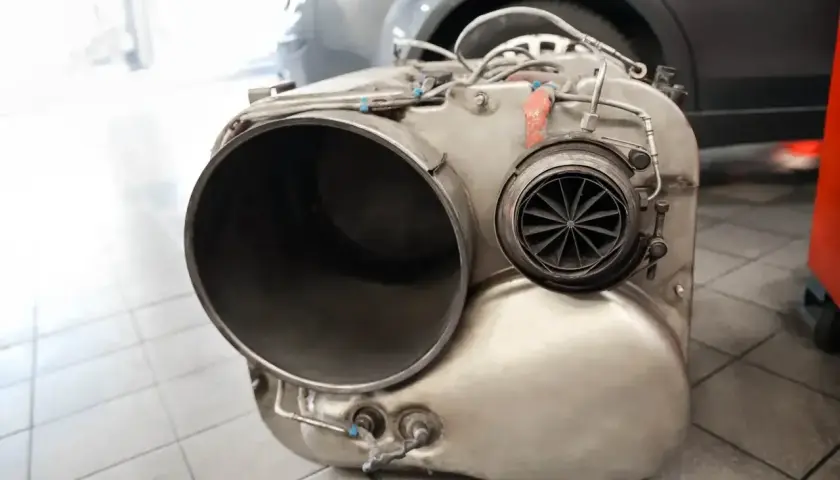 Element układu wydechowego, prawdopodobnie po usuwaniu filtra DPF. Widać dużą rurę i turbinkę.