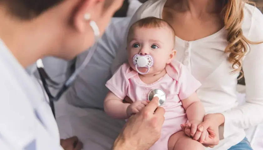 Un médecin examine un bébé avec un stéthoscope, vérifiant les symptômes de la coqueluche.