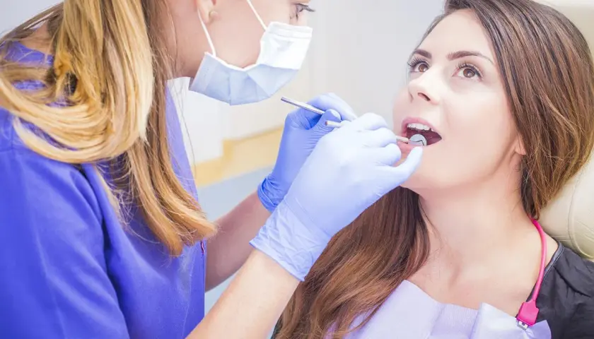 Dentystka bada jamę ustną pacjentki, szukając ewentualnych zmian.