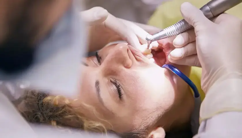 Pacjentka u dentysty, trwa zabieg. Czy leczenie kanałowe jest na NFZ? Warto sprawdzić, bo czasem można zaoszczędzić.