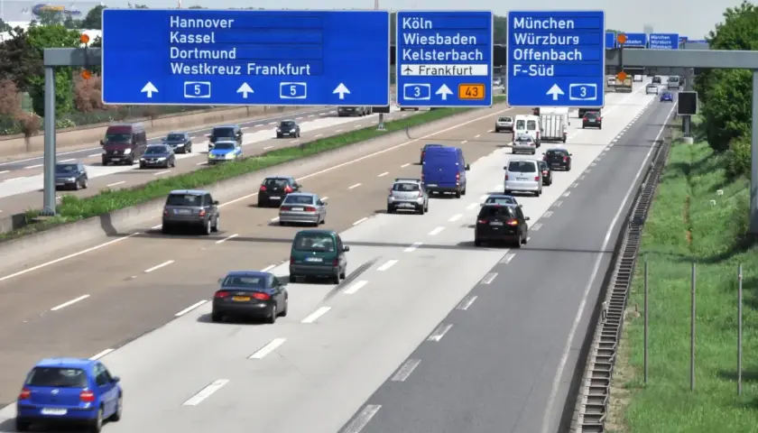 Autostrada w Niemczech z tablicami kierunkowymi do Kolonii, Frankfurtu i Monachium. Pytanie: czy w Niemczech są płatne autostrady?
