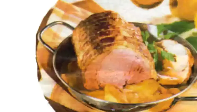 Un rôti de porc aux pommes, doré et juteux, servi dans un plat avec des quartiers de pommes et des herbes fraîches.