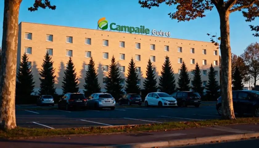 Façade de l'hôtel Campanile Guéret avec parking et arbres.