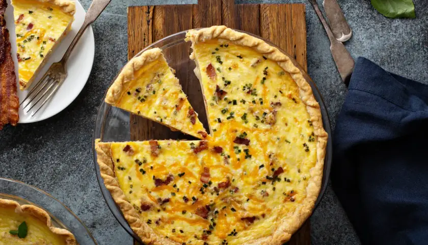Une quiche au bacon et fromage, parfaite pour une recette quiche facile. Une part est déjà servie avec du bacon croustillant.