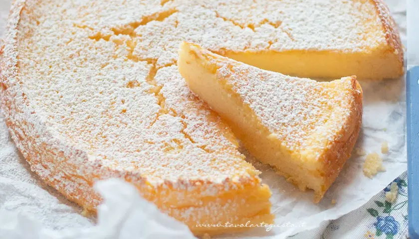 Deliziosa torta ricotta e limone, soffice e spolverata di zucchero a velo, con una fetta tagliata.