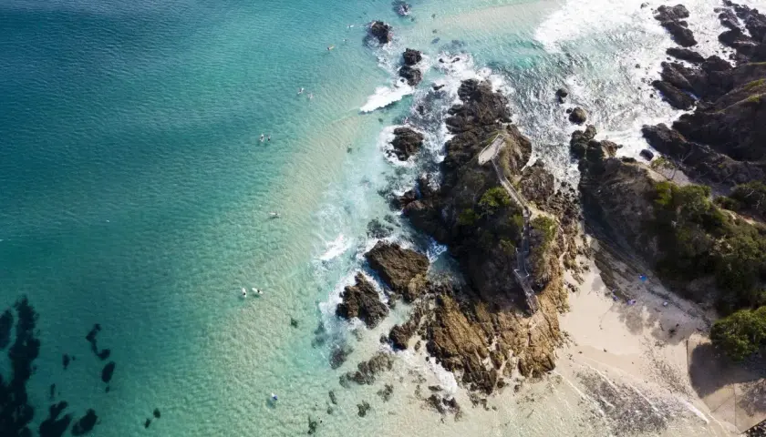 Türkisblaues Meer, Surfer und felsige Küsten – ein Bild von traum reiseziele, das zum Träumen einlädt.