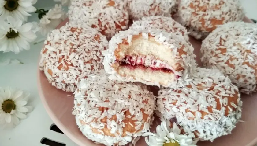 Pyszne ciastka biszkoptowe z nadzieniem owocowym i wiórkami kokosowymi, wyglądają jak małe śnieżne kuleczki.
