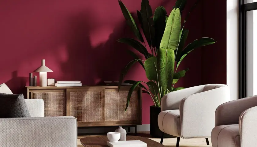 Elegancki salon z dominującym kolorem burgund. Jasne meble i drewniana komoda z rattanem tworzą przytulną atmosferę.