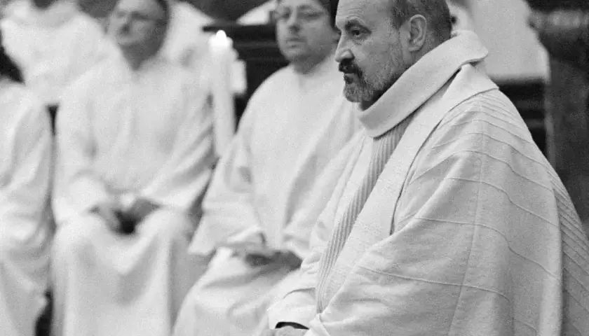 Mężczyzna w szacie, być może agnostyczka, siedzi w tłumie w białych szatach.