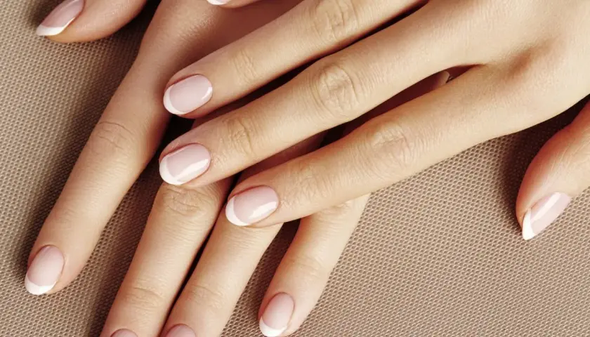 Dłonie z perfekcyjnym manicurem french kombinowany. Delikatny róż i biel podkreślają elegancję.