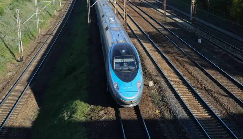 Błękitny pociąg Pendolino EIP mknie po torach.